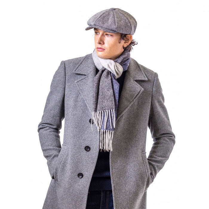Person wearing a gray coat, cap, and scarf on a white background