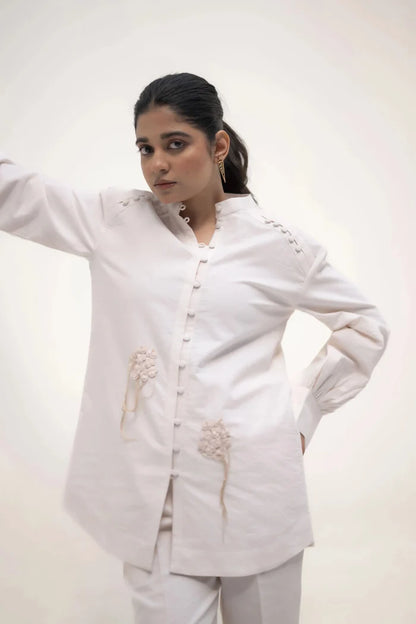 The model in white outfit, standing with one hand on her waist, looking slightly to the side with a calm expression.