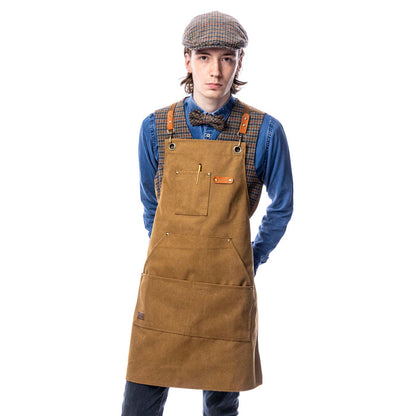 A person wearing a brown canvas utility apron with multiple pockets and adjustable straps, standing against a white background.