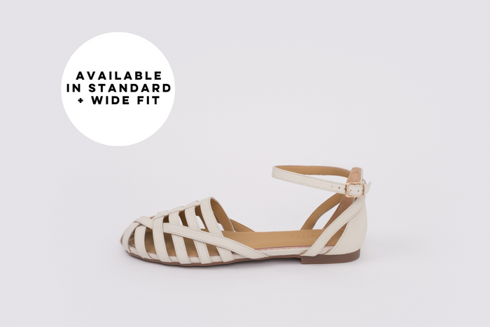 Womens large sized  flat shoe on a light gray background with text 'Available in Standard + Wide Fit'.