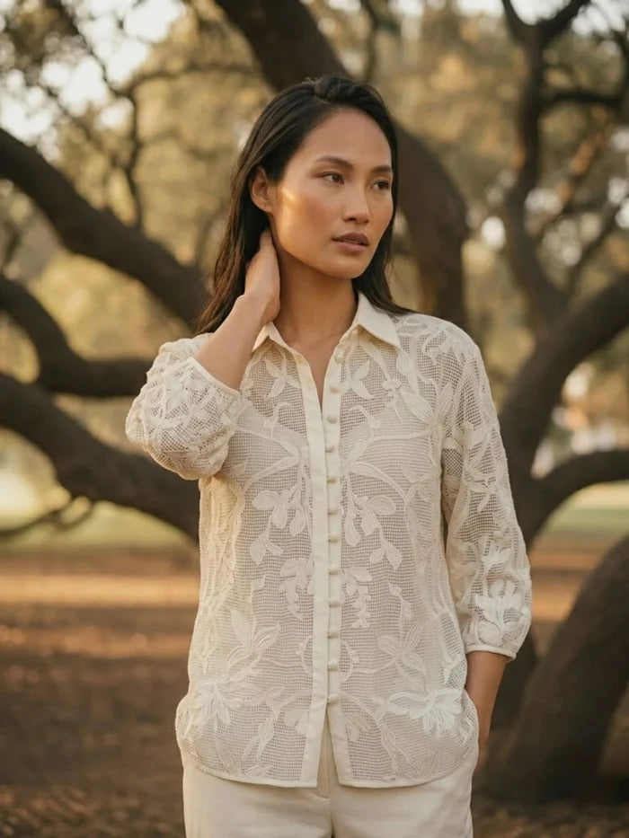 Woman posing in ivory crochet summer lace shirt, side angle view, breathable floral lace casual women’s shirt.