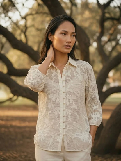 Woman posing in ivory crochet summer lace shirt, side angle view, breathable floral lace casual women’s shirt.